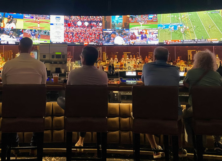А group of people watching sport on tv at a bar